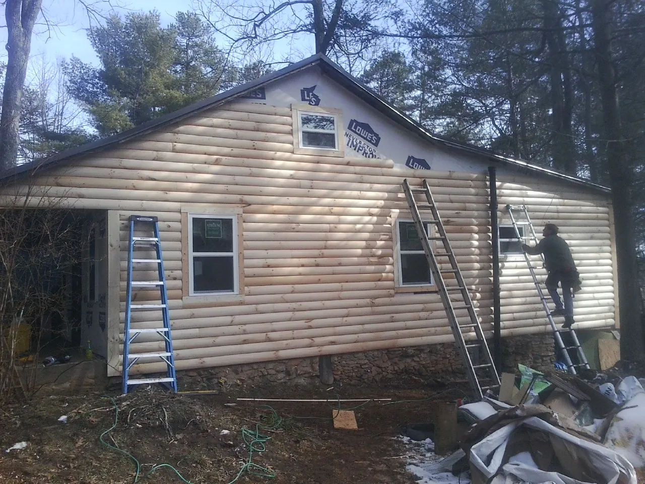 Ladders set against fresh log siding during an exterior remodel in Clifton Heights