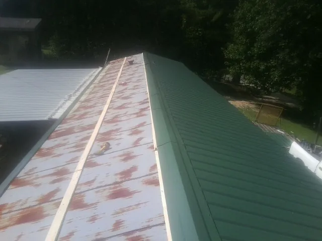 Old rusted panels beside newly installed green metal roofing — Wind Damage Roof Repair by Roofing Brothers in Clifton Heights