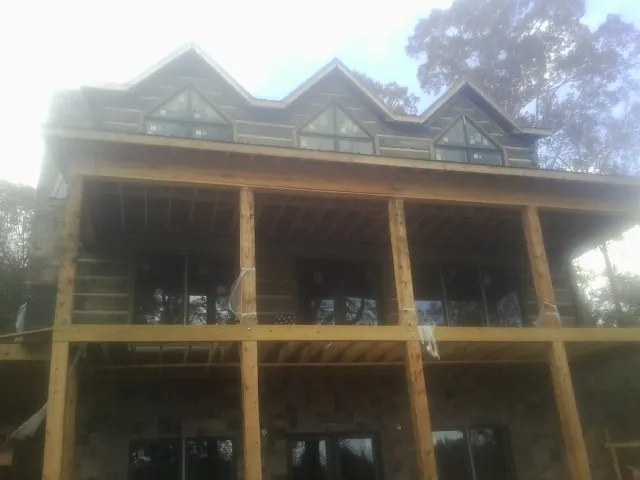 Dormers and porch framing on a large log home under construction — Roof Coating work by our crew in Clifton Heights