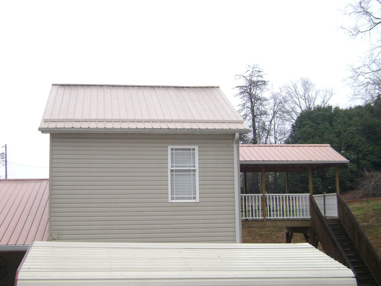 Tan metal roofs on a two story addition and attached porch, from a Roof Replacement job in Clifton Heights